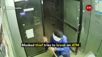 A masked thief tries to break into an ATM