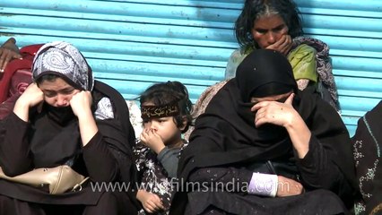 Shia women cry as the Muharram procession passes through
