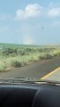 Car Drives Through Highway Crossing Dust Devil