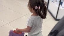 Little girl runs around the mall, dragging her stroller behind her