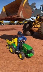 Un niño carga un tractor de juguete con una excavadora real