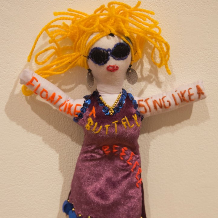 Frau zieht Stoffpuppen-Baby mit Stoffpuppenmann groß