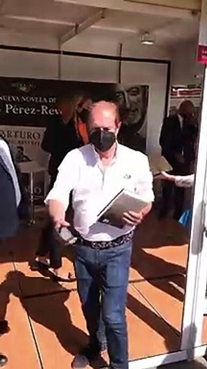 Una azafata limpia los libros antes de ser firmados por Pérez-Reverte