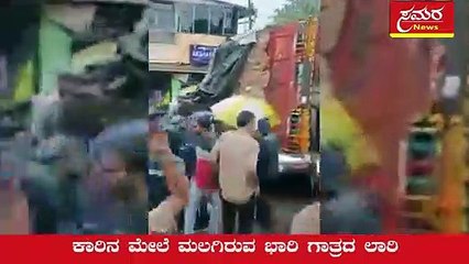 ಕಾರಿನ ಮೇಲೆ ಮಲಗಿರುವ ಭಾರಿ ಗಾತ್ರದ ಲಾರಿ A huge lorry lying on top of a car