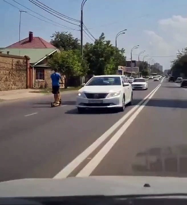 Ce débile roule à trottinette entre les voitures à contre-sens