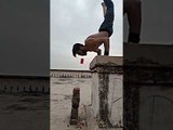 Fitness Model Holds Bottle in His Mouth While Doing Handstand Push-up on Platform