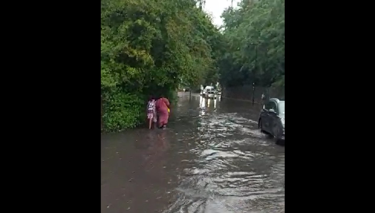 Torrential lane forced commuters to wade through knee-deep water in London this afternoon