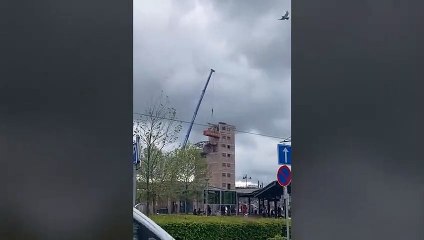 Une pelleteuse dans un conteneur perché en hauteur avec une grue