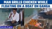 Prayagraj: Man seen grilling chicken, smoking hooka floating on Ganga | Oneindia News *News