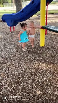 Sweet baby boy holds hands with little girl at the park