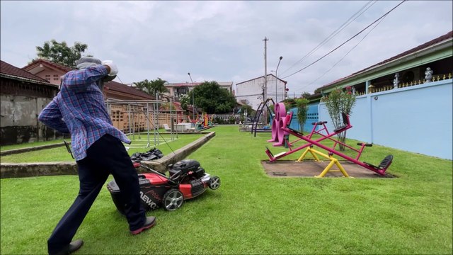 Mowing the grass in the children's playground in Sai Noi district, Nonthaburi province, Thailand