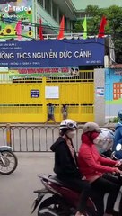 Hai em bé đứng nhìn qua khe cửa trước cổng trường