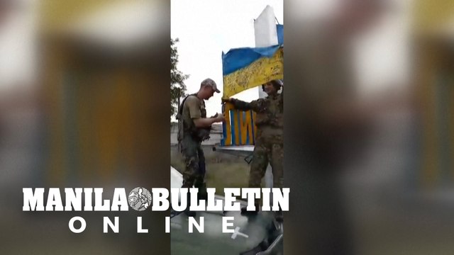 Ukrainian soldiers raising a flag at the entrance to Lyman