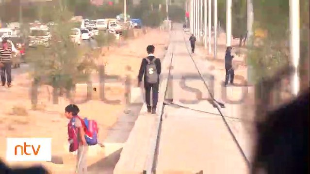 ¿Qué es esto? : Vehículos parqueados, peatones y niños que transitan por la plataforma del Tren Metropolitano