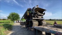 Thai farmers loading a harvesting machine onto a trailer in Thailand