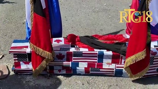 Plizyè militan Dèlma 30 abiye yon sèkèy senbolik ki gen foto Ariel Henry ak divès drapo lòt peyi.