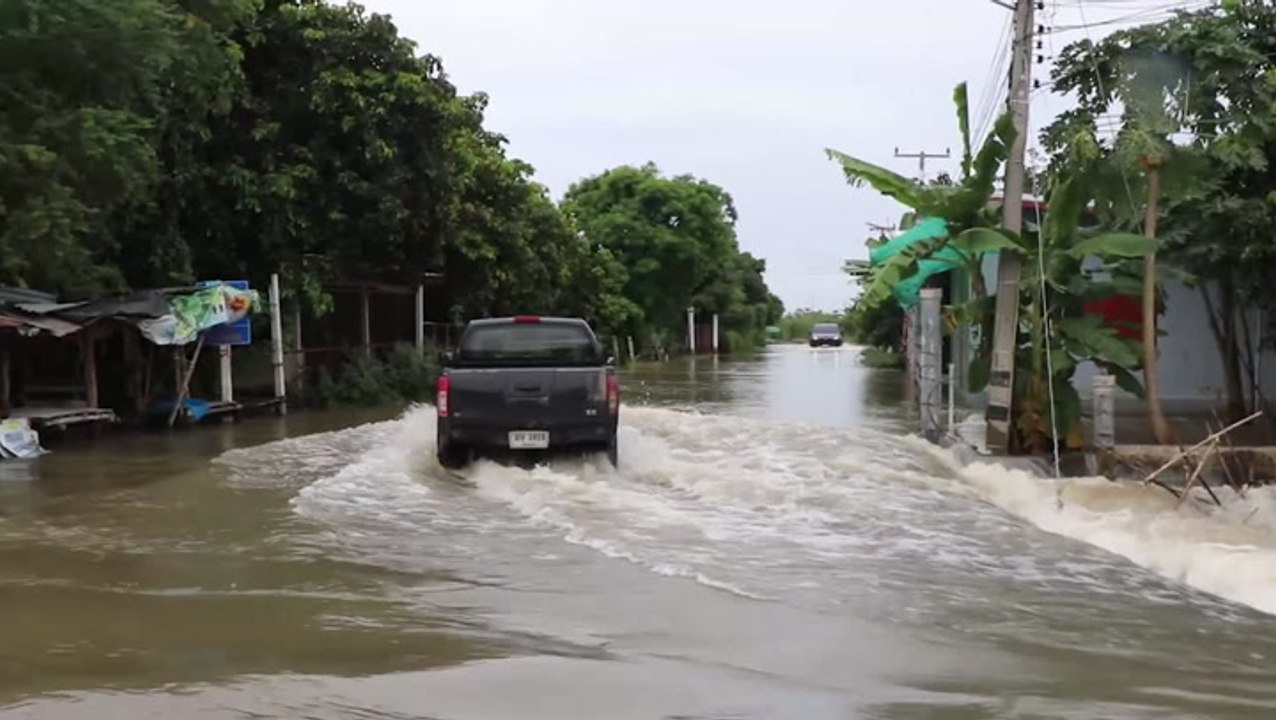 Trucks drive on submerged road as flooding continues in Thailand