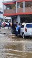 Un homme porte une femme à une voiture dans une rue inondée - Buzz Buddy
