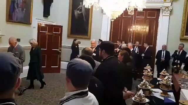 King Charles and Queen Consort Camilla pose for photos beneath a portrait of the late Queen Elizabeth II