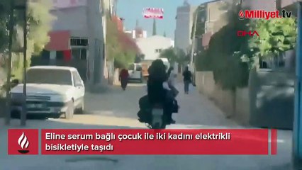 Eline serum bağlı çocuk ile iki kadını elektrikli bisikletiyle taşıdı
