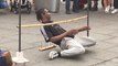 Gutsy street performer attempts to go under a low limbo bar while avoiding the sharp nails under it
