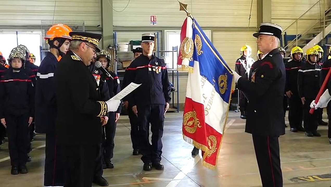 Le Préfet accroche la médaille du mérite et du dévouement sur le drapeau des sapeurs pompiers du Jura.