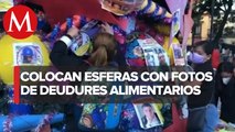 Mujeres oaxaqueñas colocan árbol de navidad con imágenes de deudores alimentarios