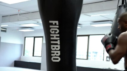 A Man Practicing A Fighting Maneuver Over A Heavy Bag