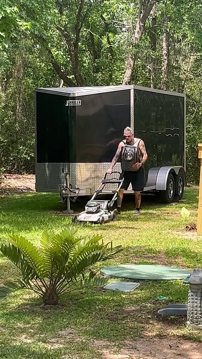 Man Mows Lawn While Carrying Cat in Backpack