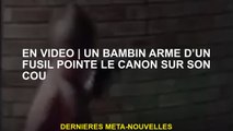 En vidéoUn enfant en bas âge armé d'un fusil pointe le canon sur son cou
