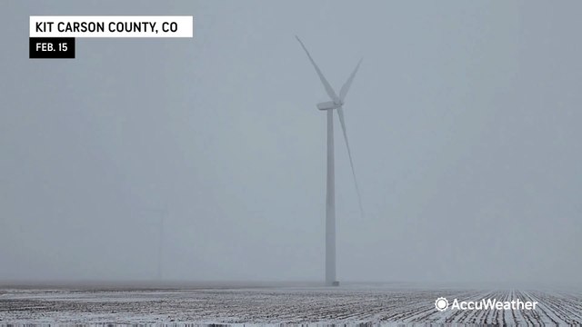 Wind turbines spin in the midst of blowing snow