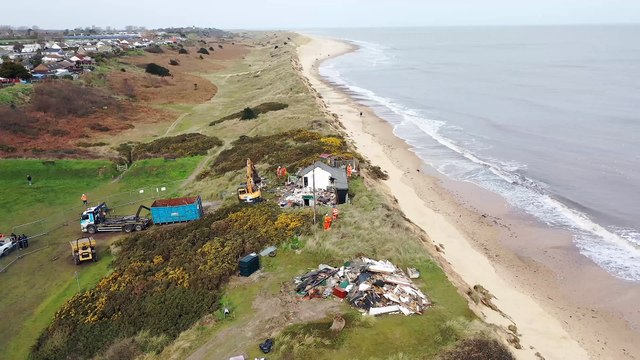 Footage shows construction workers tearing down homes close to a cliff edge - over fears they would fall into the sea