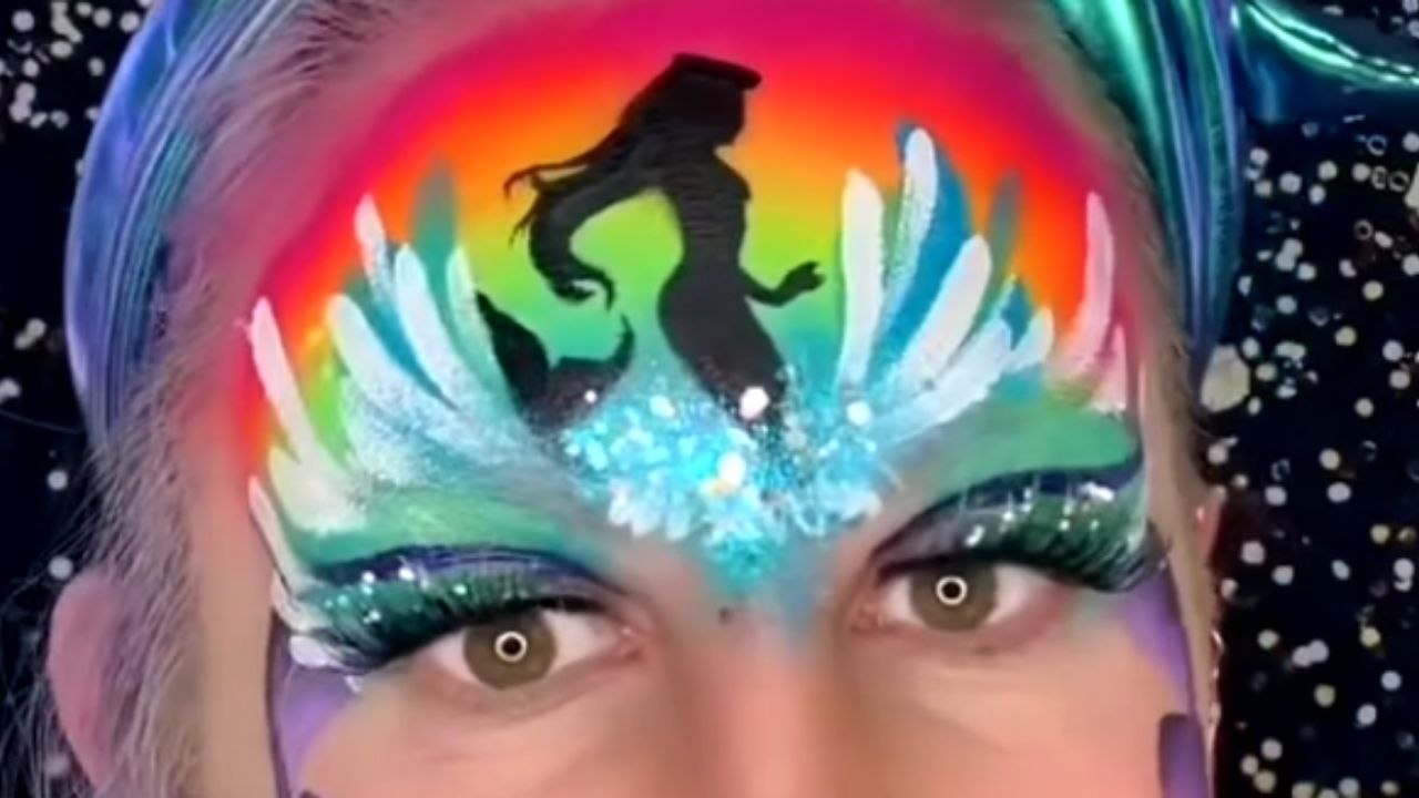 Face painter adds magic to her mermaid design by singing a song from The Little Mermaid