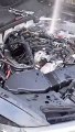 Un mecánico quita las bujías del motor de un Audi A6 que se ha llenado de agua, y el agua es lanzada al aire por la rotación de los pistones.