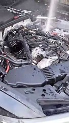 Un mecánico quita las bujías del motor de un Audi A6 que se ha llenado de agua, y el agua es lanzada al aire por la rotación de los pistones.
