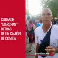 Cubanos marchan detrás de un camión con comida.