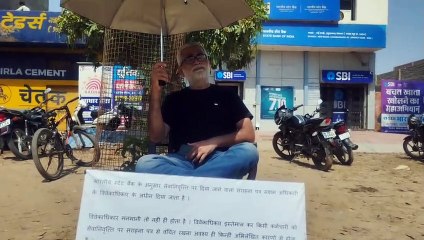 Retired bank employee standing on strike against bank management amidst drizzle