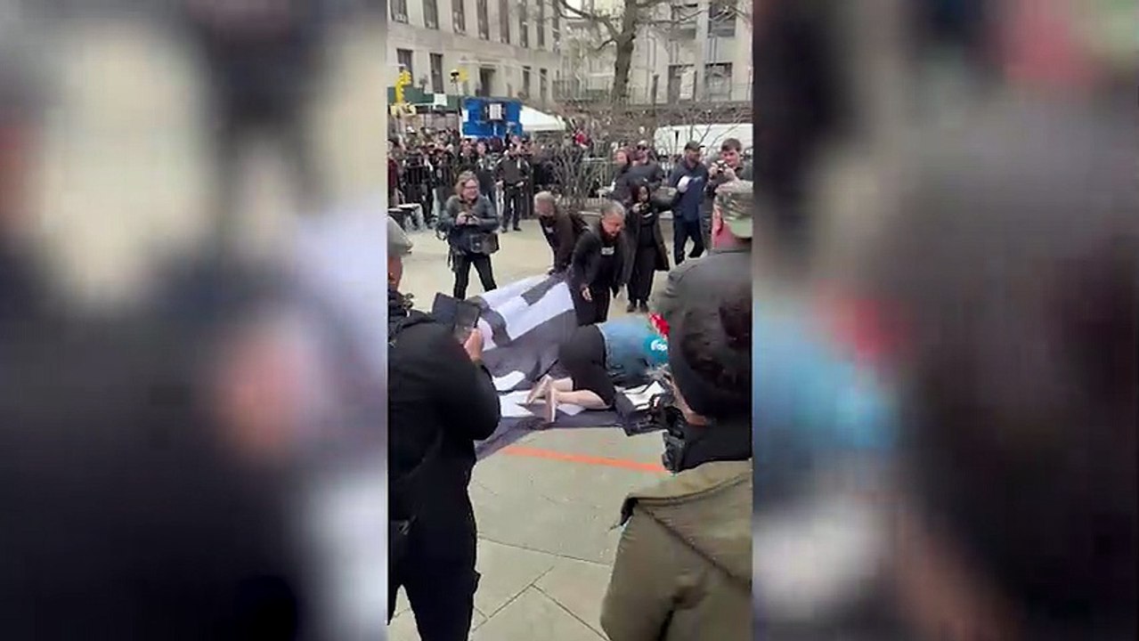 Trump supporter Juliet Germanotta throws herself onto a "Trump Lies" flag outside the courthouse entrance