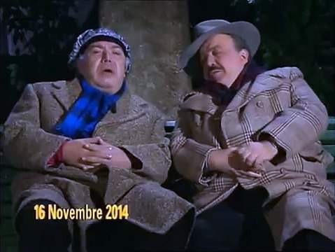 Lino Banfi e Maurizio Costanzo seduti su una panchina da anziani, mentre parlano della vita di personaggi famosi - scena del 1990