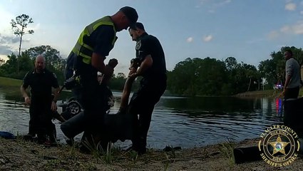 Moment police and civilians pull driver out of upside-down submerged car