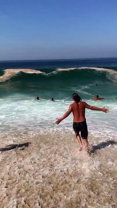 Des touristes s'amusent dans des vagues vraiment très très grosses