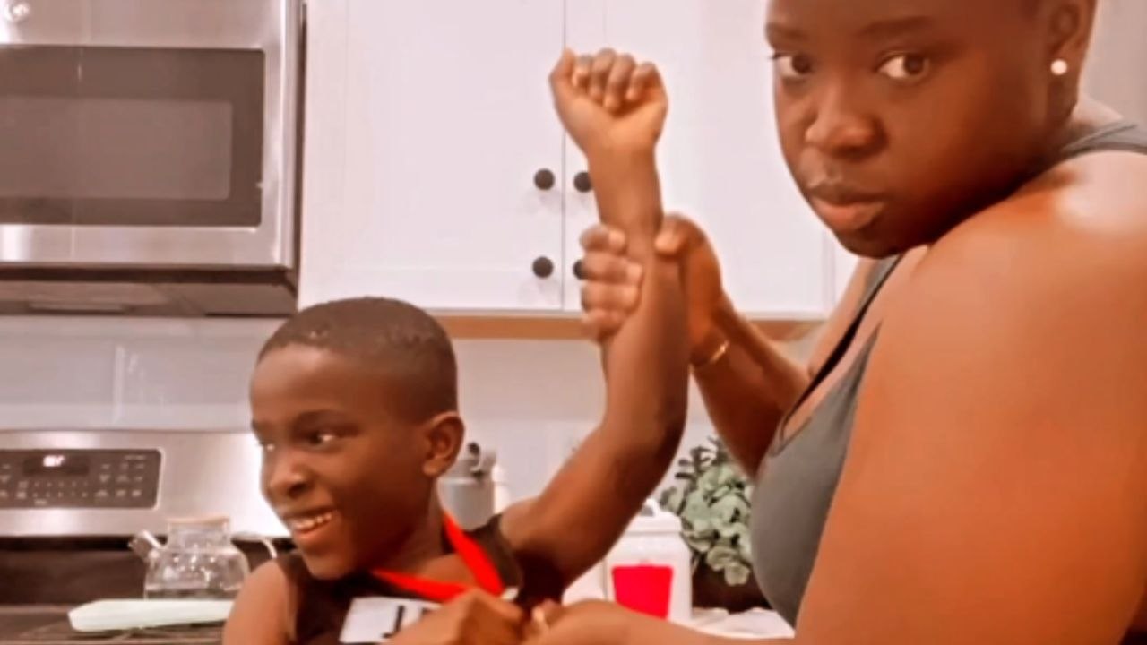 Kid cannot stop laughing as mother helps him apply a deodorant