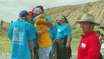 Migrantes se abrazan y derriban simbólicamente el muro entre México y EEUU