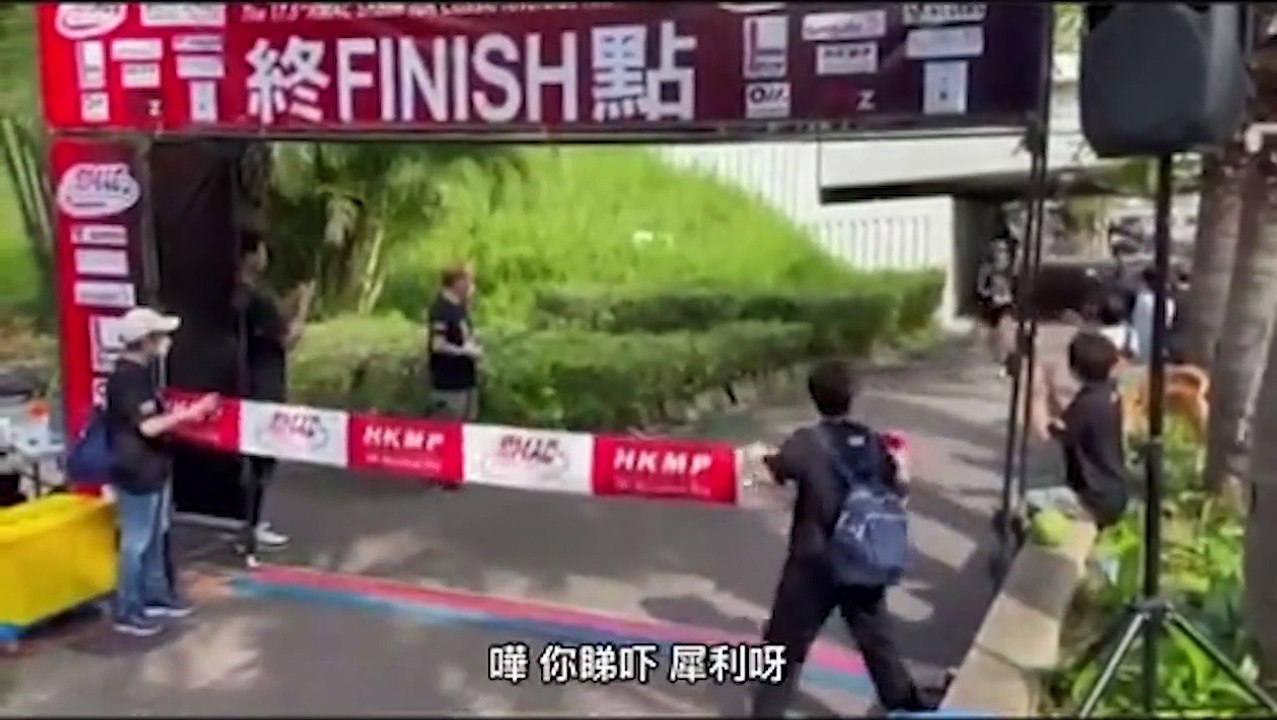 Une bénévole a bien du mal à gérer le ruban de la ligne d'arrivée d'une course
