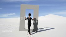 Woman wanders through desert doorframe, wide - stock video African American fashion model walks through doorframe in desert on sunny day