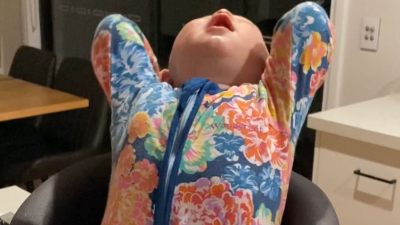 Silly baby has mastered the art of making dinner time with family a giggle gala