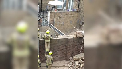 Firefighters attend the scene of a house that collapsed in Finsbury Park