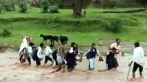 children reaching school crossing the river in the rain