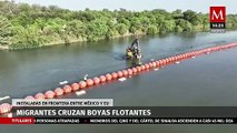 Migrantes cruzan las boyas flotantes que están sobre el Río Bravo para llegar a EU