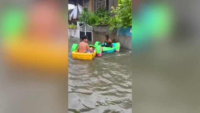 Light-hearted locals play in boats on flooded road after typhoon Doksuri hits Philippines